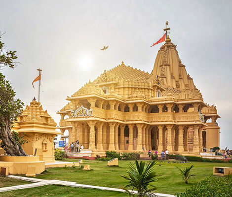 Somnath temple with a lawn view and people walking around
